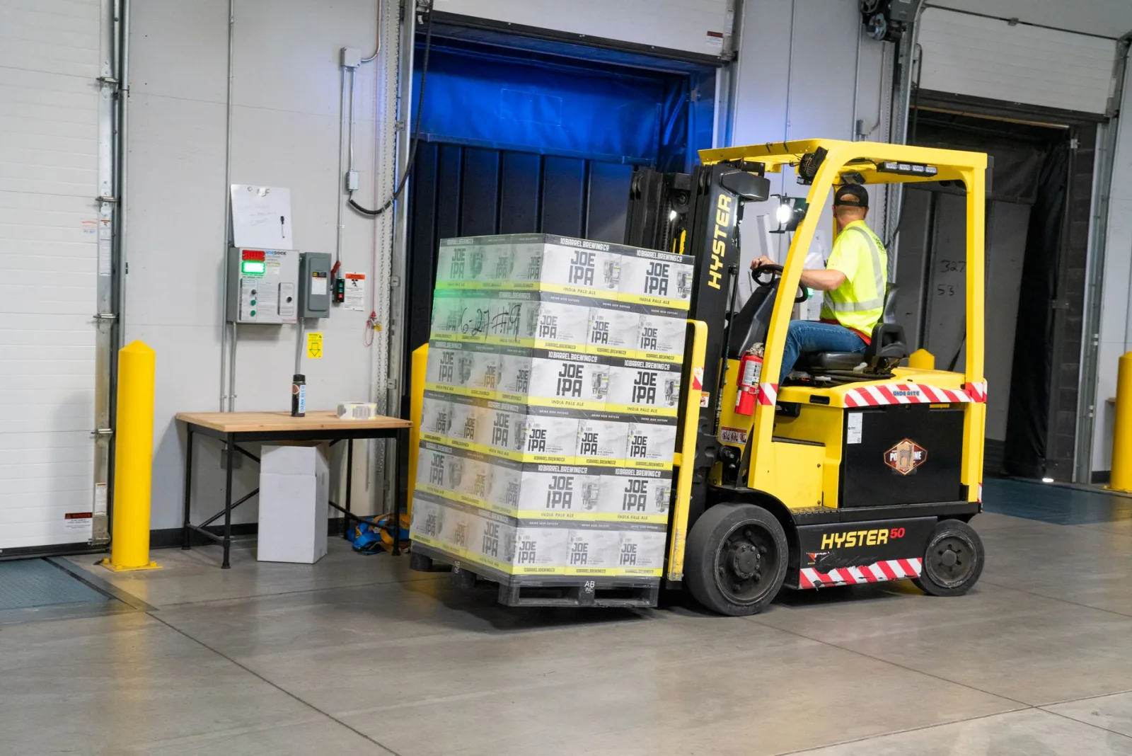 Antrepo içinde forkliftle taşınan, streç filmle sarılmış paletli yük
